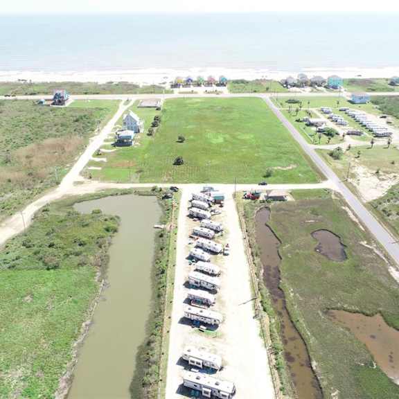 a parking lot with several cars is surrounded by grassy fields.