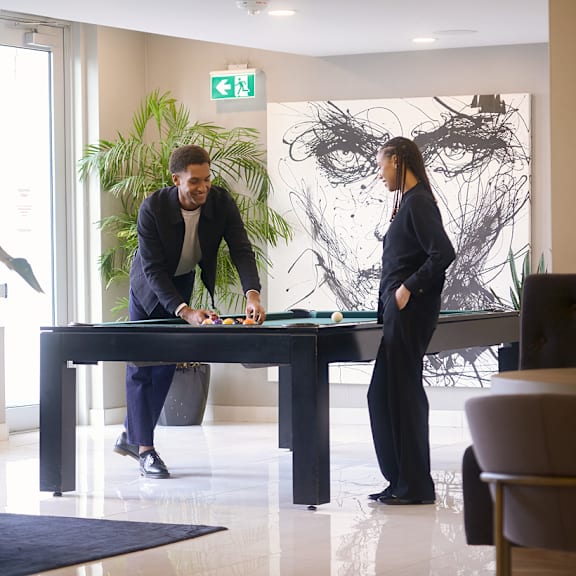 two people are standing in a room with a large painting on the wall and a green exit sign above them at the dale apartments , ottawa, ontario