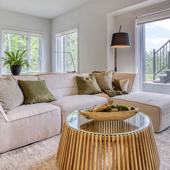 a living room with a beige couch, a wooden coffee table, and a staircase in the background.
