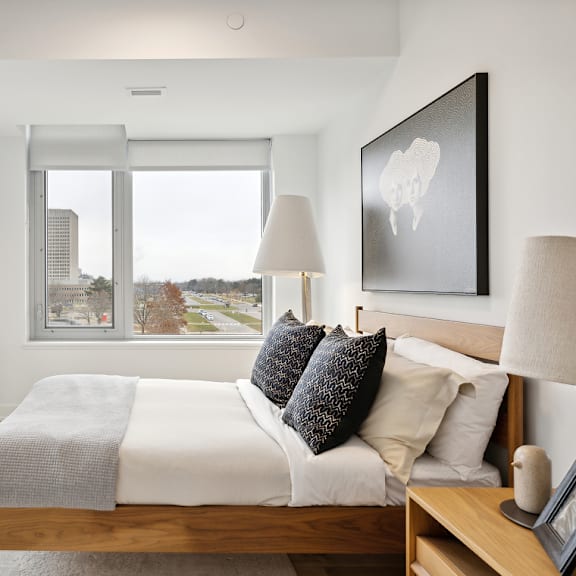 a bedroom with a large bed and a view of the city at the dale apartments , ottawa