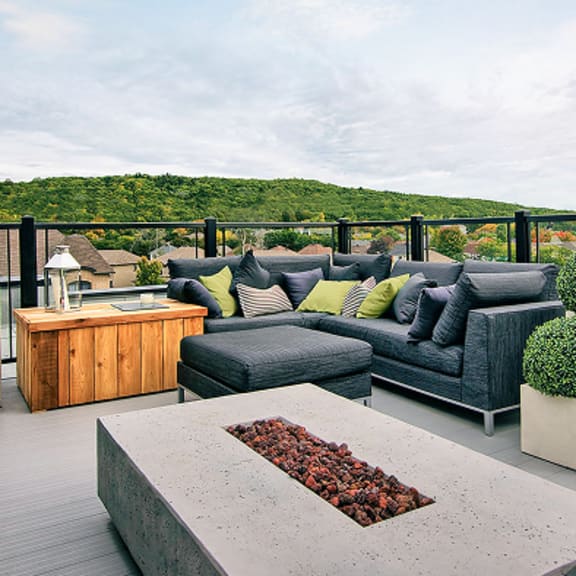 a modern outdoor seating area with a fire pit and cushioned furniture.