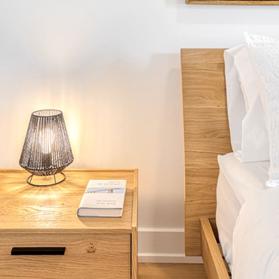 a lamp on a bedside table next to a bed.