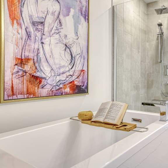 a bathroom with a white tub and a painting on the wall.