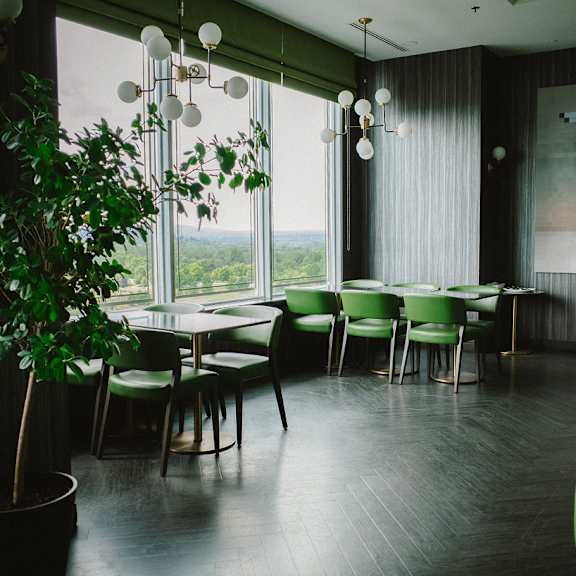 a room with green chairs and a green table with a potted plant in front of a window.