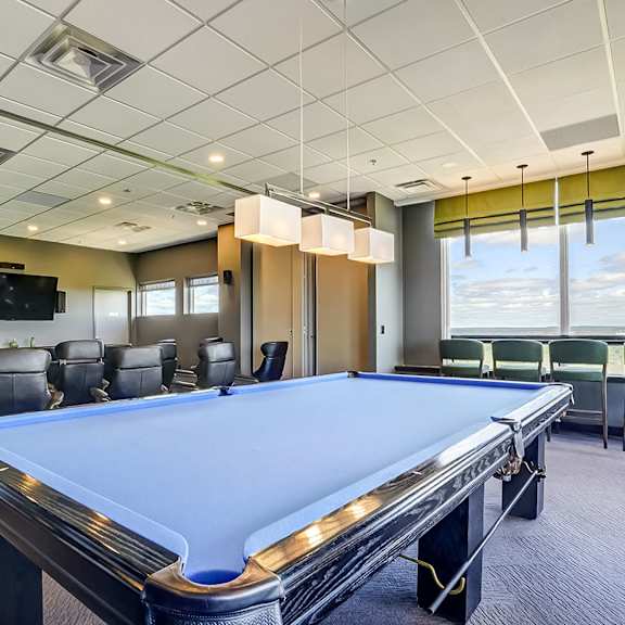 a pool table in a room with a television and chairs.