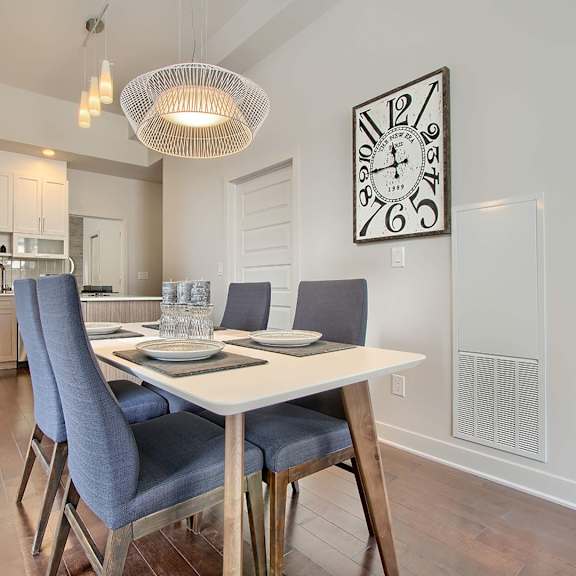 a dining room with a table set for two and a clock on the wall.