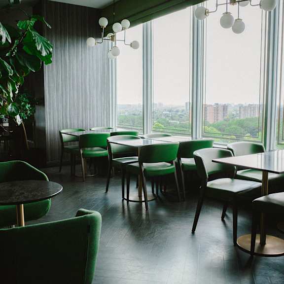 a restaurant with green chairs and tables.
