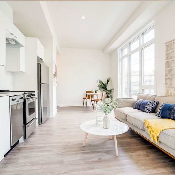 a modern kitchen with a grey sofa and wooden floors.