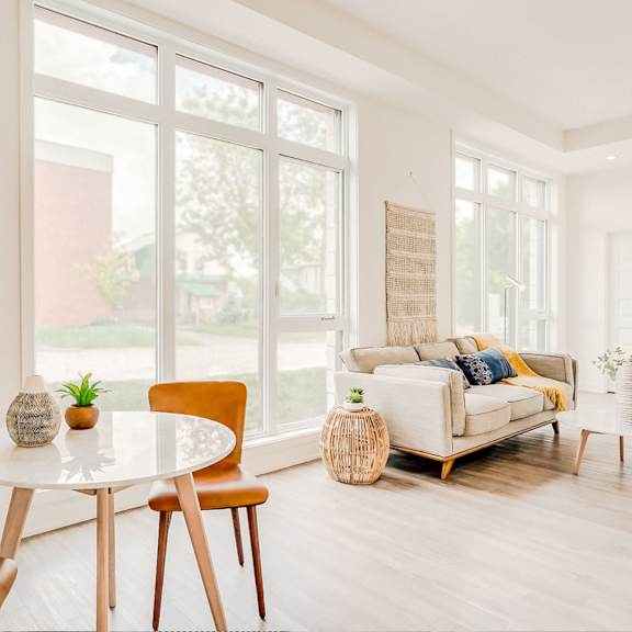 a living room with a white table and chairs, a couch, and a plant.