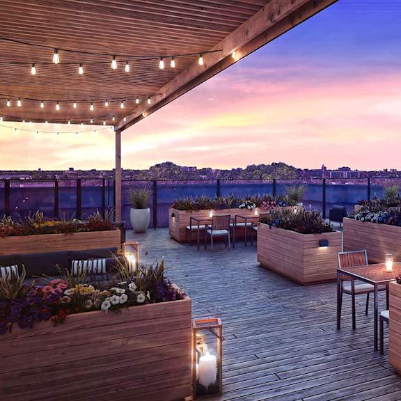 a rooftop garden with wooden planters and tables under a twilight sky.