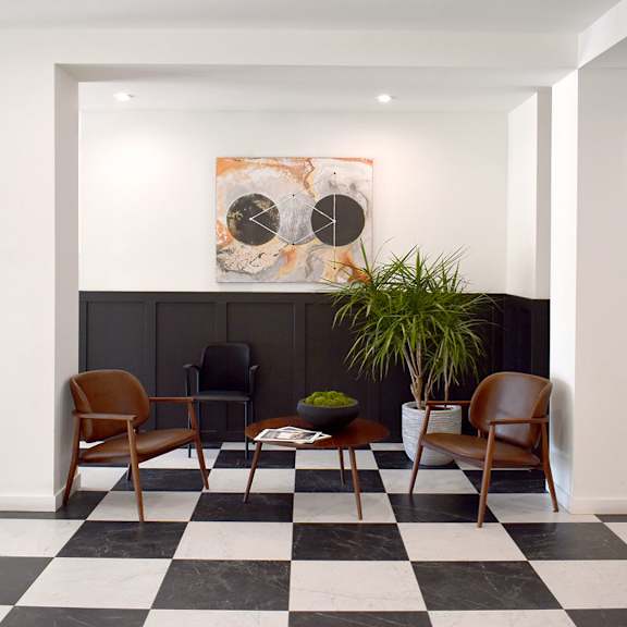 a black and white checkered floor with a chair and a table in the middle.