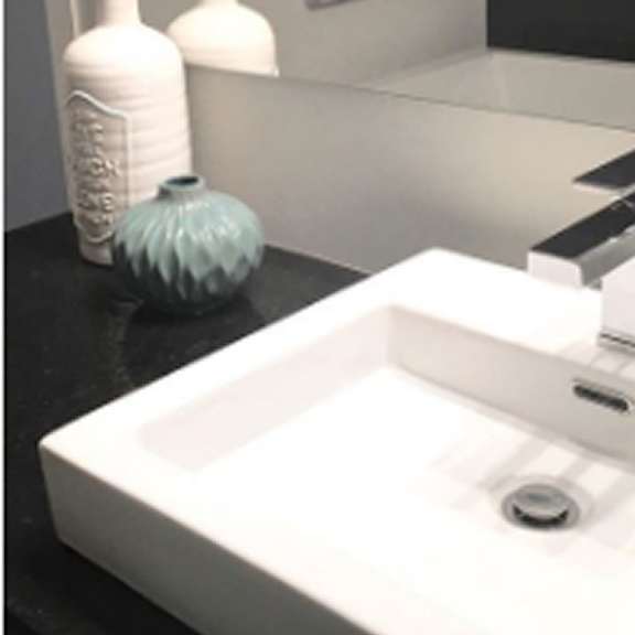 a white sink with a silver faucet and a blue vase.