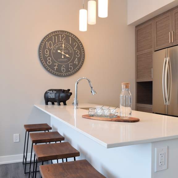 a kitchen with a white countertop and a clock on the wall.
