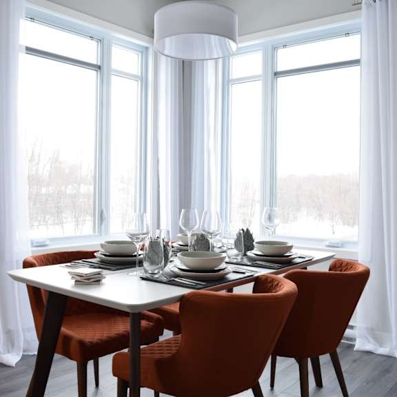 a dining table with four chairs and a white tablecloth is set for a meal.