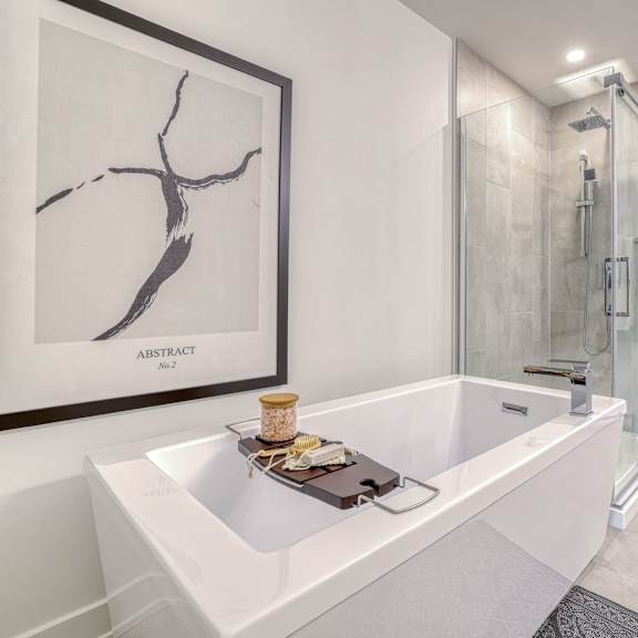a white bathroom with a white tub and a framed picture on the wall.