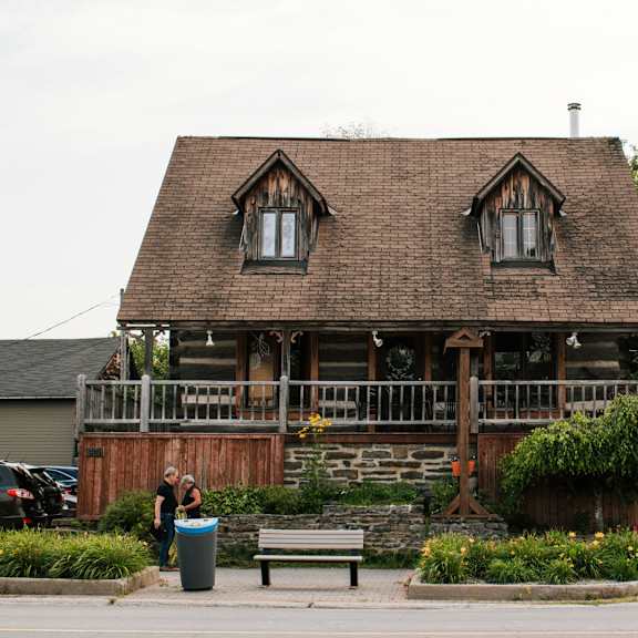 a building with a brown roof and a balcony with plants on it.