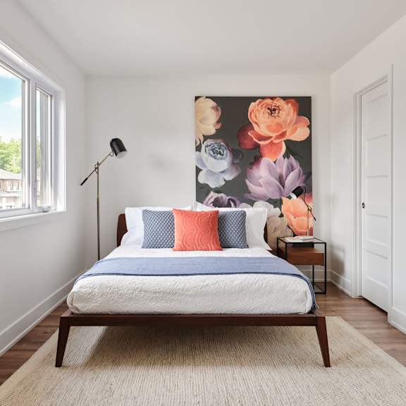 a bedroom with a bed, a lamp, and a floral wallpaper.