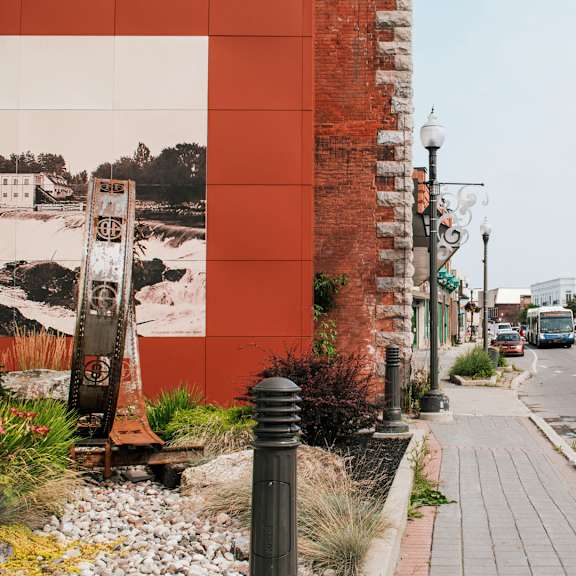 a street with a red building and a white sign on the sidewalk.