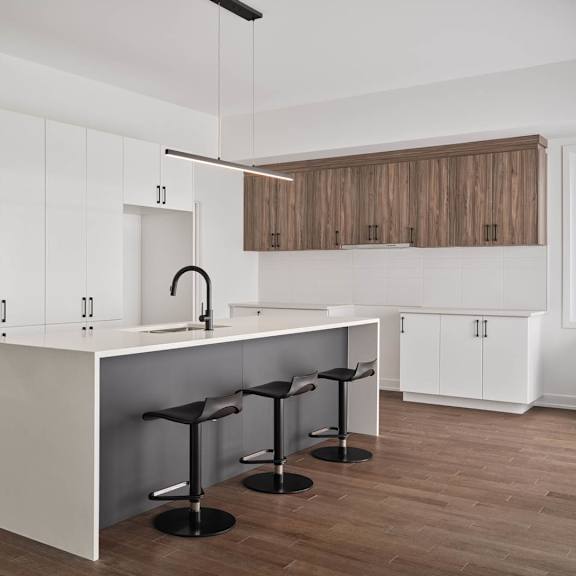 a modern kitchen with a white island and bar stools.