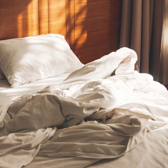 a bed with white pillows and sheets is messy and unmade.