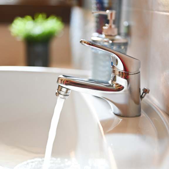 a white sink with a silver faucet and running water.