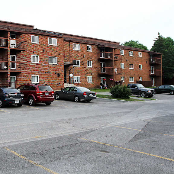 a parking lot in front of a red brick apartment building.