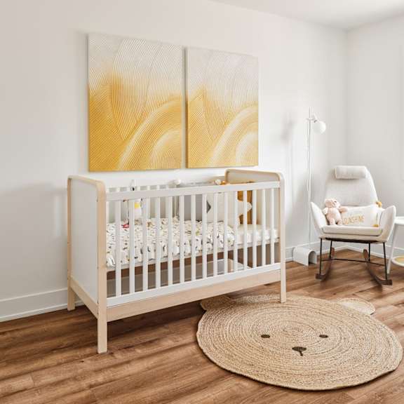 a baby room with a crib, a chair, and a painting on the wall.