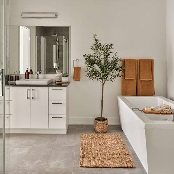 a bathroom with a white tub, sink, and a tree in a pot.