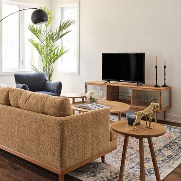 a living room with a tan couch, a wooden table, and a television.