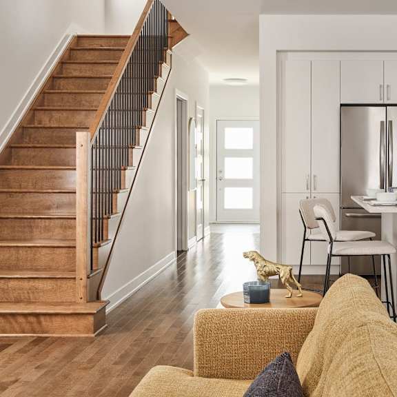 a modern kitchen with a white refrigerator and stove, a dining table with chairs, and a staircase with wooden steps.