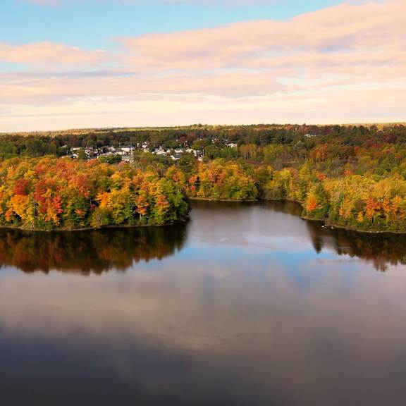 a serene landscape with a lake, trees, and a small town in the distance.