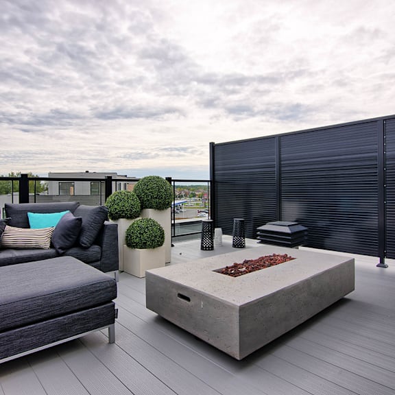 a modern outdoor seating area with a grey couch and a concrete coffee table.