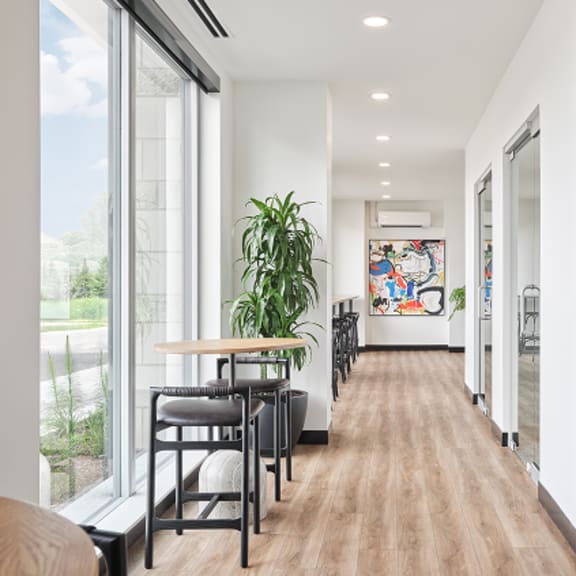 a long hallway with a table and chairs on the left and a painting on the right.