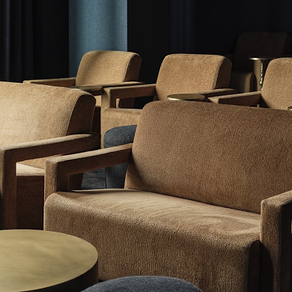 a set of brown chairs and a table are arranged in a waiting area.