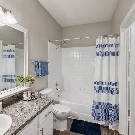 a bathroom with a white toilet, sink, and striped shower curtain.