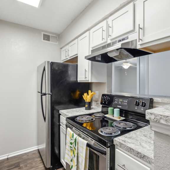a kitchen with a black fridge and stove top oven.