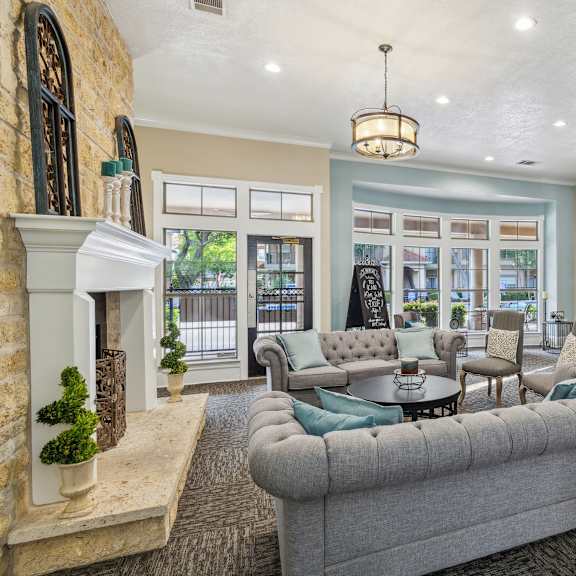 a common room with a grey couch and a fireplace with a cafe in the back.