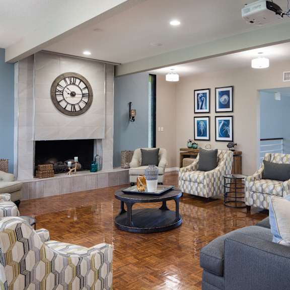 a common room with a fireplace and a large clock on the wall.