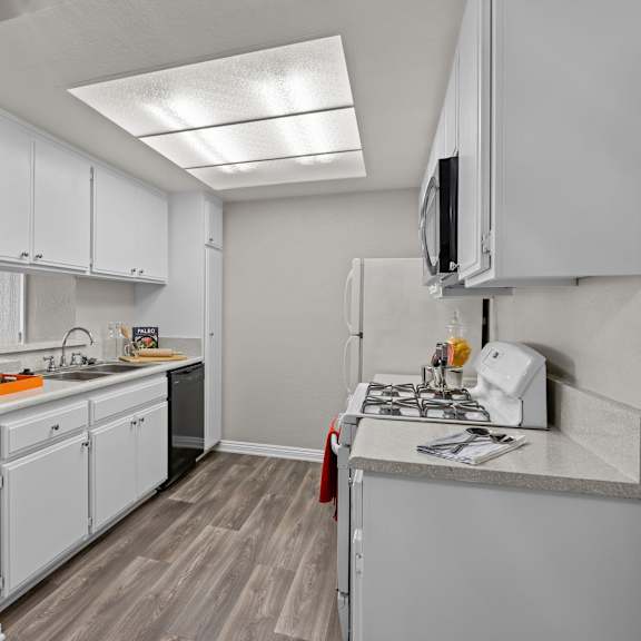 a kitchen with white cabinets and a grey counter top.