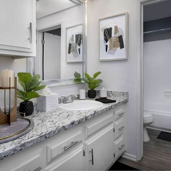 a bathroom with a marble countertop and white cabinets.