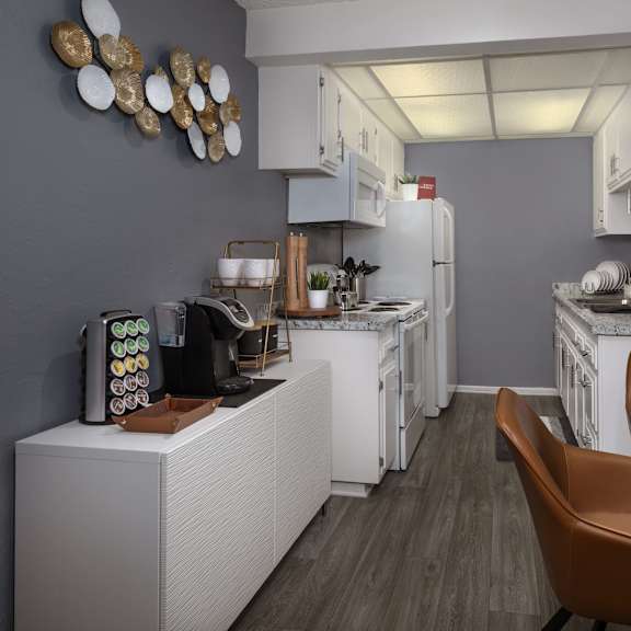 a modern kitchen with white appliances and brown leather chairs.