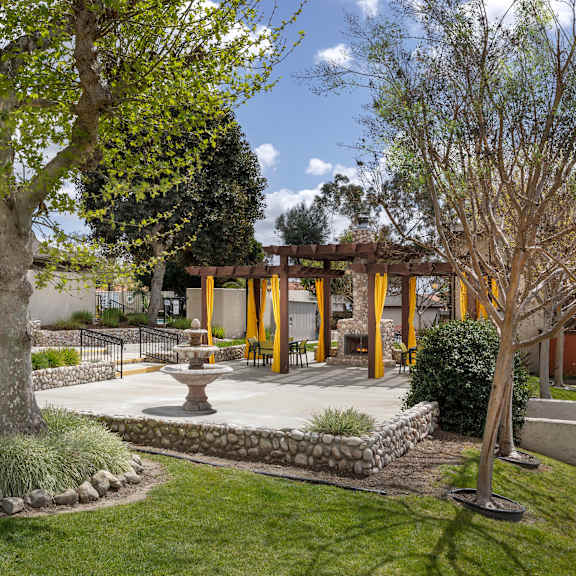a common area patio with a fireplace and chairs.