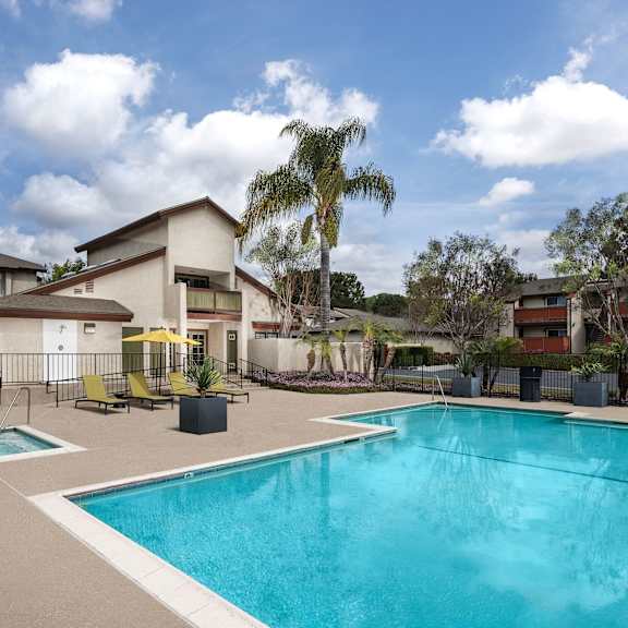 a swimming pool in a residential area surrounded by trees and houses.