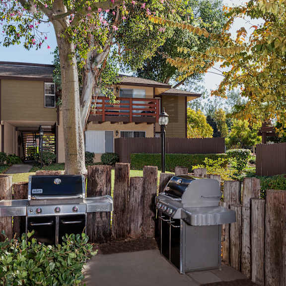 a bbq grill is in the middle of a yard with a building in the background.