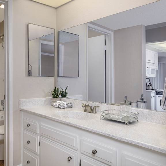 a white bathroom with a toilet, sink, and mirror.