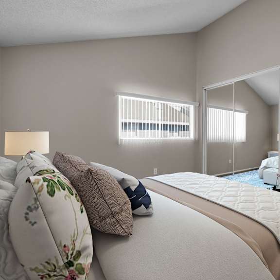 a bedroom with a large bed and a mirrored closet door.