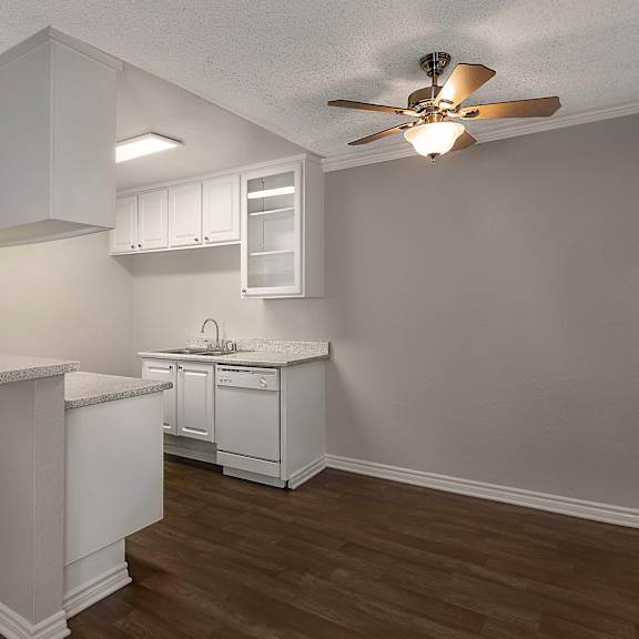 a kitchen with white cabinets and a ceiling fan.