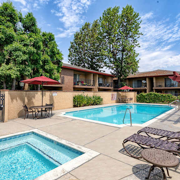 a pool area with a small pool and a larger pool with chairs around it.