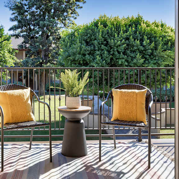 two chairs with yellow pillows sit on a patio.