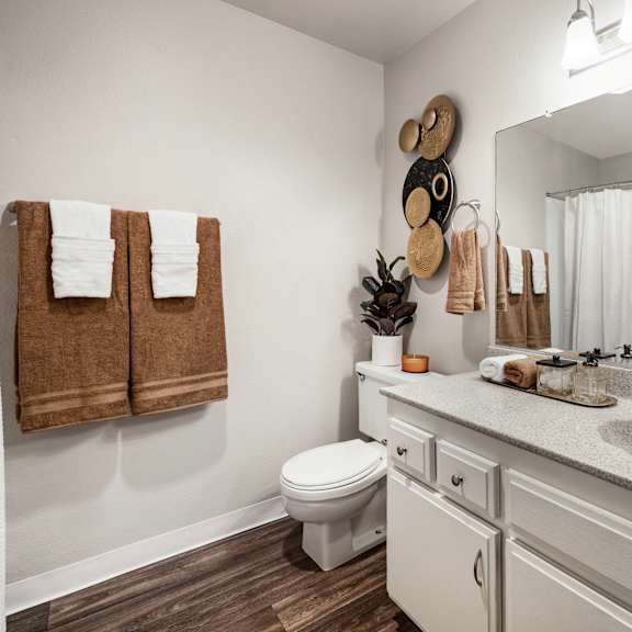 a bathroom with a toilet, sink, mirror, and towel rack.